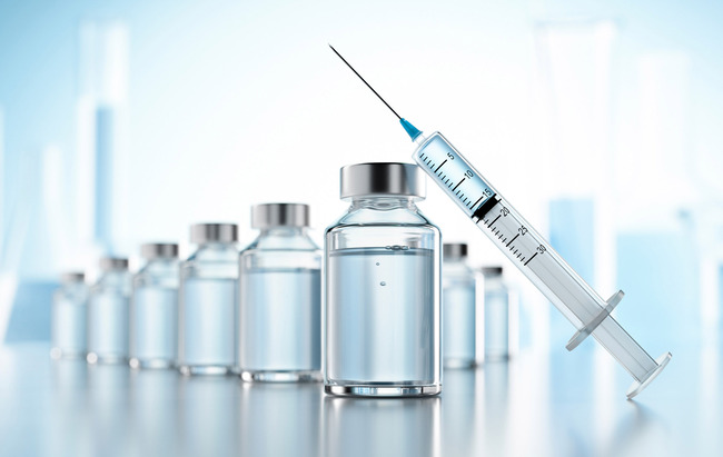 Impfstoffspritze und Ampullen (Quelle: peterschreiber.media/shutterstock.com)