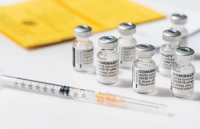 Comirnaty COVID-19-Impfstoff-Ampullen neben Impfpass und Spritze (Quelle: r.classen/Shutterstock.com)