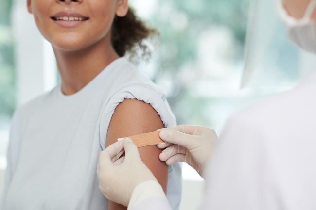 A woman receives a plaster on the vaccination site after vaccination A woman receives a plaster on the vaccination site after vaccination